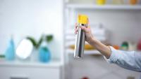 woman spraying air freshener in a house